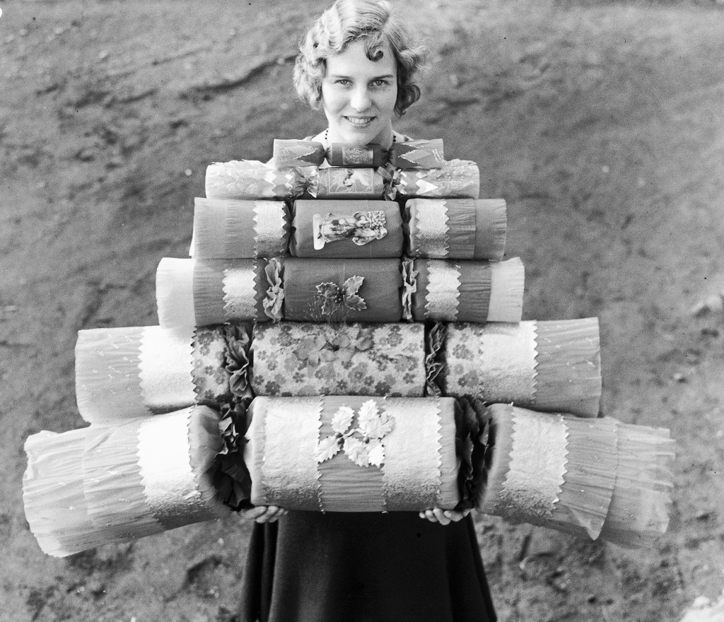 All sizes of crackers', 14 December 1932 Black and white photograph of woman holding large and small Christmas crackers