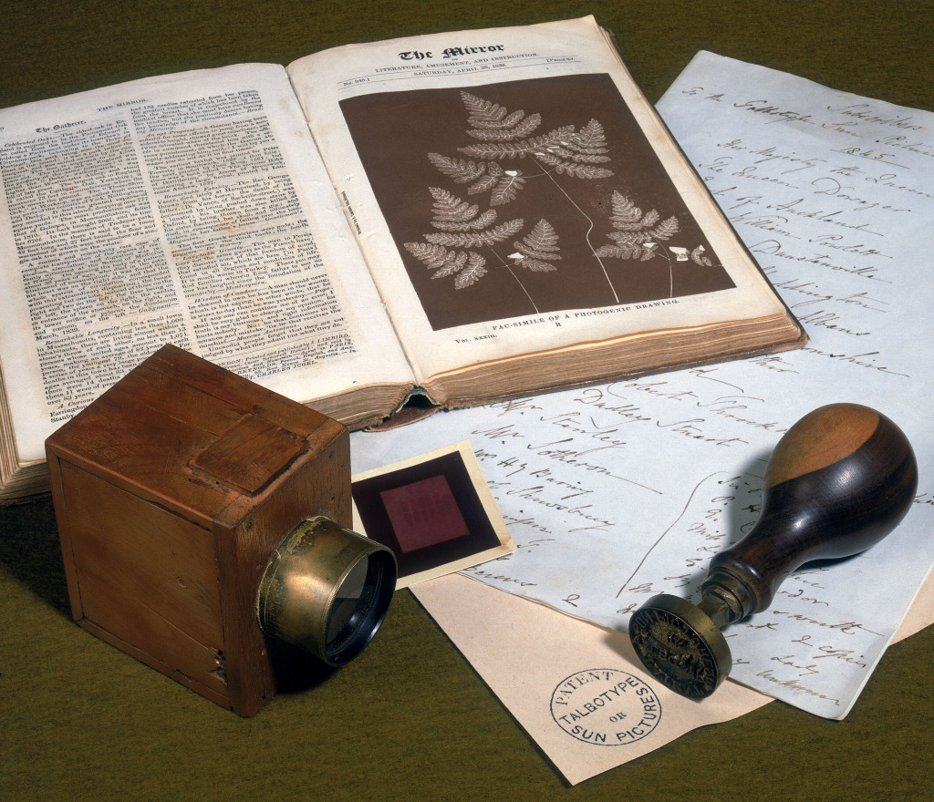 Objects associated with W H F Talbot, c 1840 A small experimental camera with a lens, produced in 1834-1836, and a metal patent stamp, embossed: 'Patent Talbotype or Sun Pictures'
