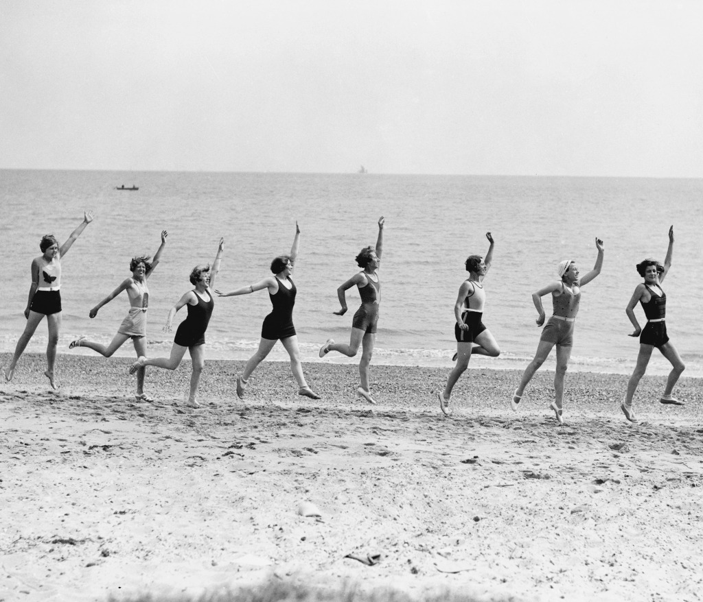 Holiday makers, Jaywick Sands, near Clacton, 18 June 1932 Black and white photograph of holiday makers dancing, running and jumping along the sand at the beach.